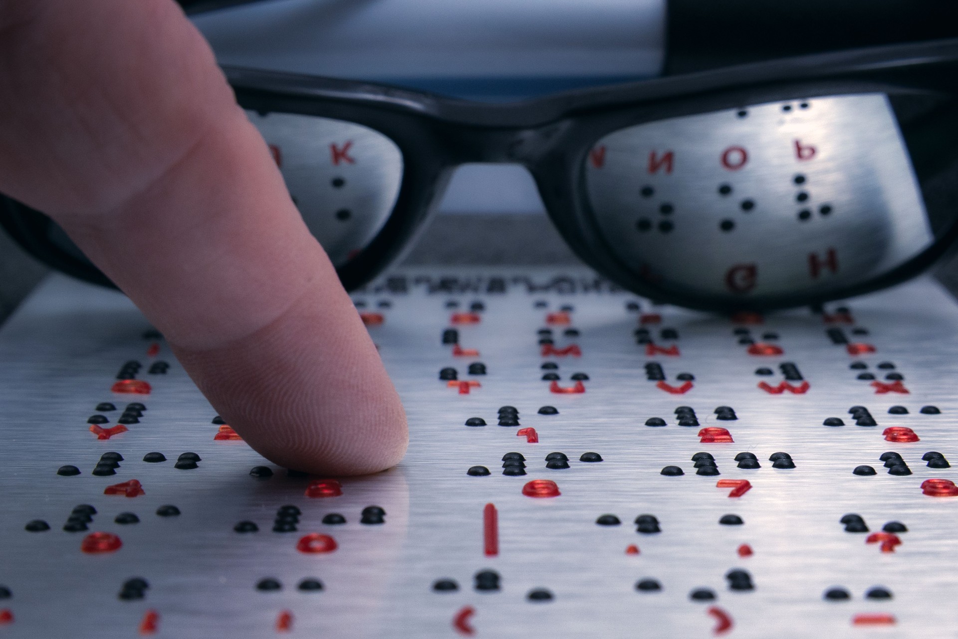 Fingertip gently exploring braille, glasses reflecting the coded language, creating a poignant image of accessibility